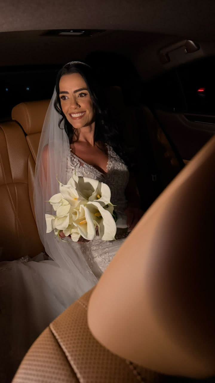 Noiva sorrindo com buquê no banco de couro